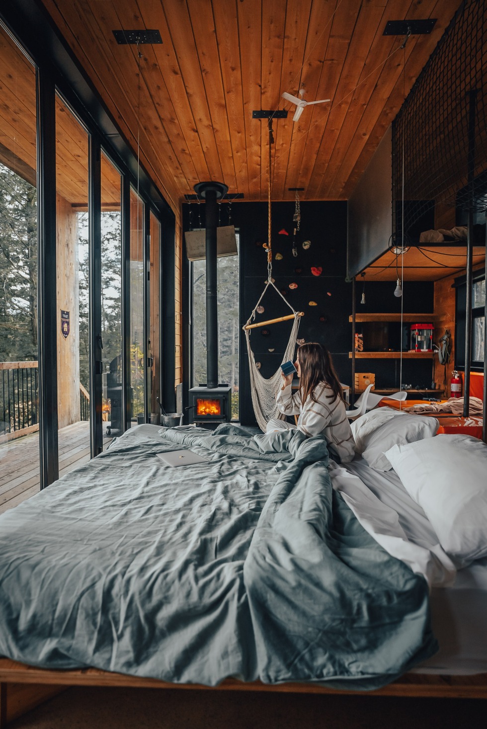 Femme buvant son café au lit dans l'un des chalets locatifs du Vertendre.