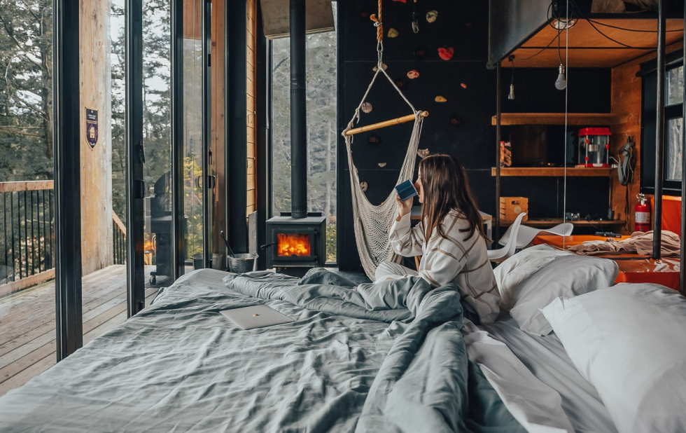 Femme buvant son café au lit dans l'un des chalets locatifs du Vertendre.