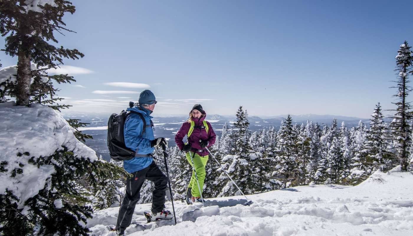 Un homme et une femme prenant une pause au sommet du Mont-Orford, alors qu'ils sont en skis.
